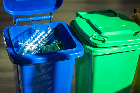 Plastic waste sorting in blue and green recycling bins at home