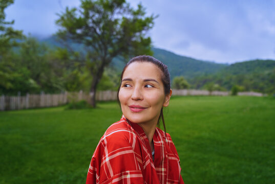 Smiling woman in red plaid shirt relaxing in the green countryside