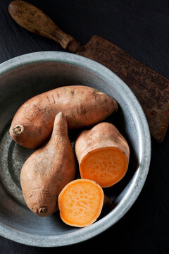 Sliced and whole sweet potato in metal bowl