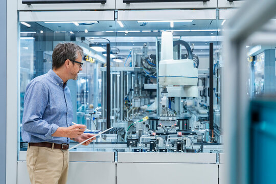 Engineer with tablet overseeing automation process in modern factory