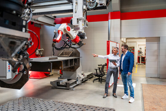 Employees discussing automation near industrial robot in factory