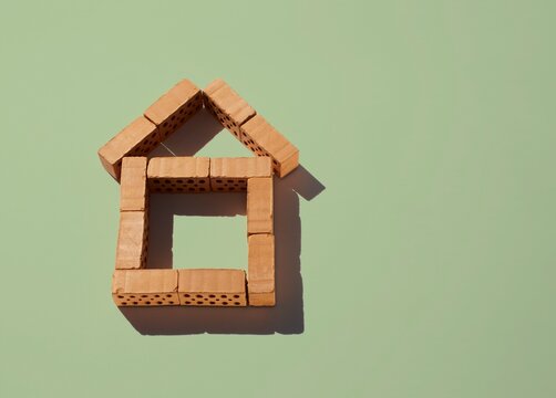 House shape made of miniature red brick on green background