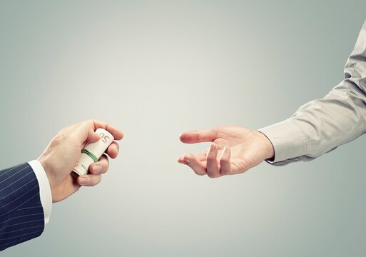 Hand offering a roll of euro money as a bribe