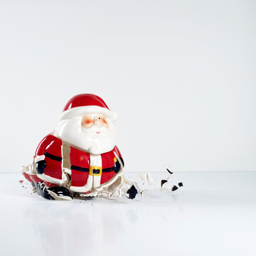 Porcelain Santa Claus figurine breaking on a white background