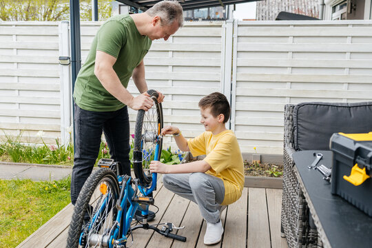 Father and son repairing a bicycle together outdoors