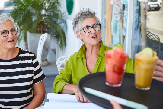 Friends surprised by healthy drinks served at an outdoor cafe