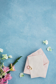Studio shot of pair of wedding rings, invitation card and flower bouquet