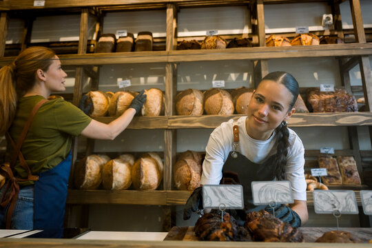 Bakery employee working behind counter with fresh bread on display