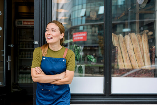 Bakery employee in apron smiling confidently outside store