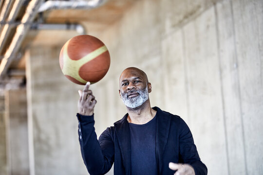 Portrait of mature businessman with basketball in modern office