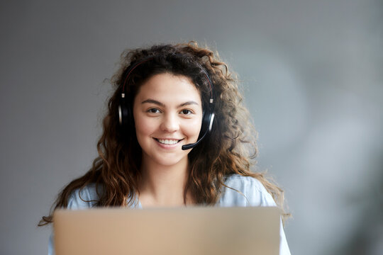 Beautiful young woman wearing headset while sitting with laptop at home