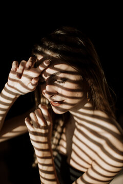 Moody indoor portrait of woman with dramatic shadow pattern