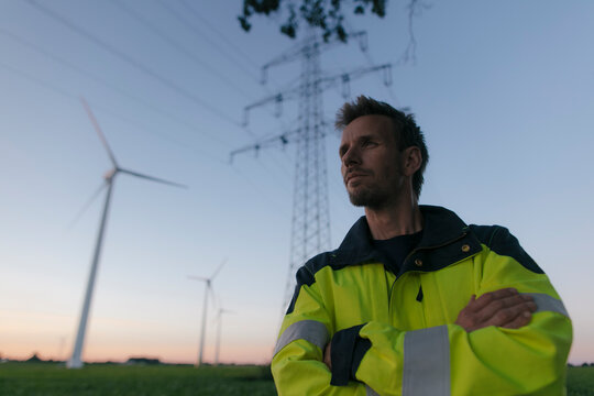 Portrait of an engineer next to a wind farm and power pole