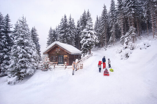 Austria, Altenmarkt-Zauchensee, family with sledges at wooden house at Christmas time