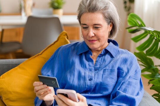 Woman using credit card and smartphone for online shopping at home