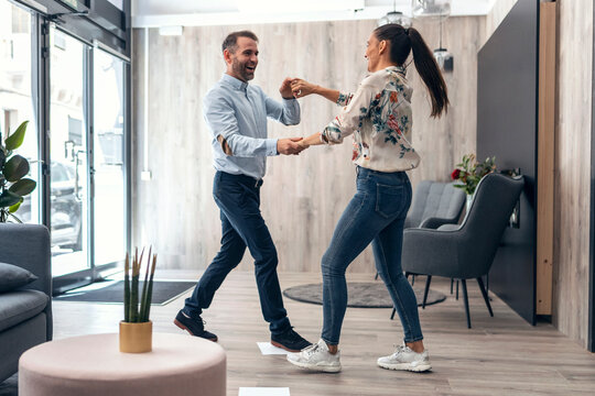 Carefree business couple dancing in office