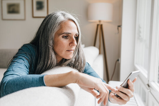 Woman sitting on the couch looking at cell phone