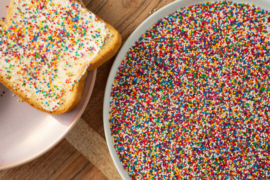 A top down view of a bowl of nonpareils rainbow sprinkles.