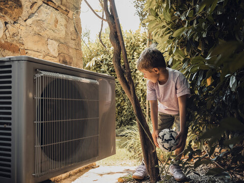 Child holding soccer ball near air conditioner in Tuscany