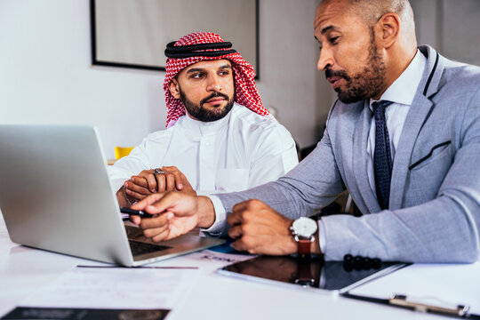 Saudi businessman and colleague discuss global strategy at office