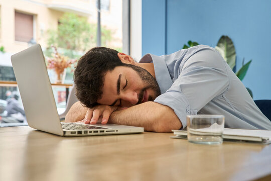 Exhausted employee sleeping on laptop at the office desk