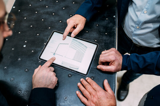 Businessmen discussing strategy using a tablet in an office setting