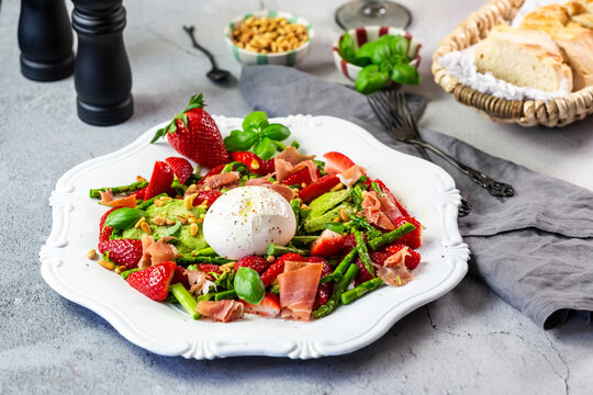 Fresh spring salad with burrata strawberry asparagus and ham