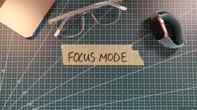Top down view of applying FOCUS MODE handwritten tape near smartphone.