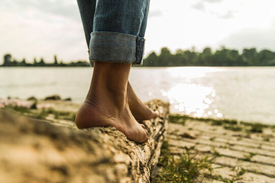 Close-up of young woman balancing on log by the riverside