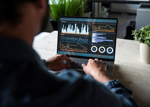 Financial specialist working on laptop with data charts in office