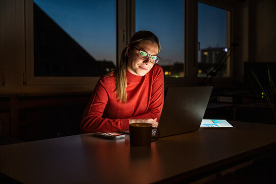 Employee working late at night on laptop in dark office