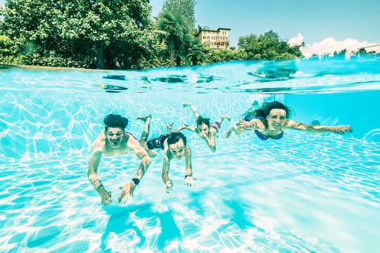 Parents swimming with children under swimming pool on sunny day