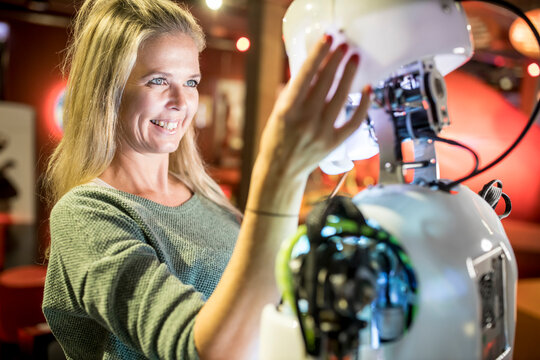 Happy technician looking at human robot at workshop