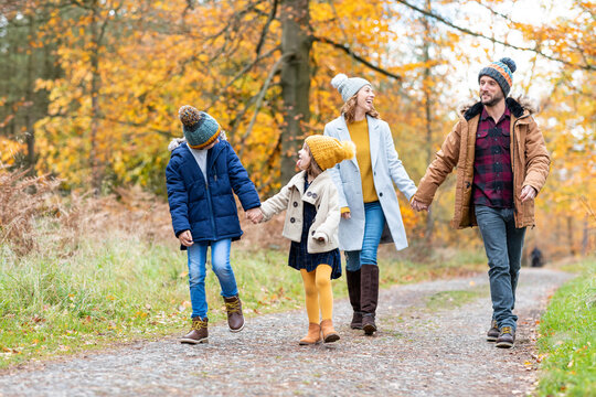 Siblings looking at each other while walking with parents in forest