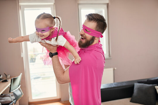 Father and daughter playing superhero and superwoman, pretending to fly