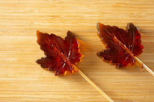 A top down view of some maple leaf hard candy lollipops.
