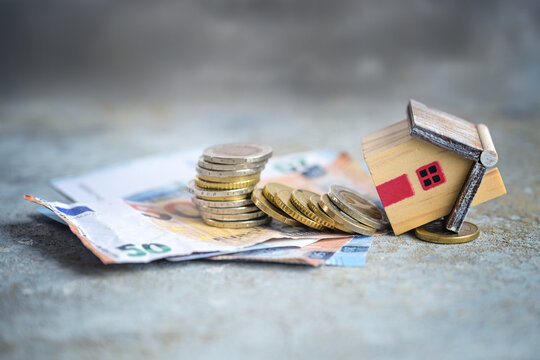 Financing failed, house model crashed down with a stack of coins and banknotes, concept for too low equity, excessive debt, or rising interest rates, copy space, selected focus