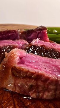A slice of medium rare steak is pulled away revealing its juicy pink center and charred crust, capturing the texture and indulgence of a perfectly cooked steak, static shot