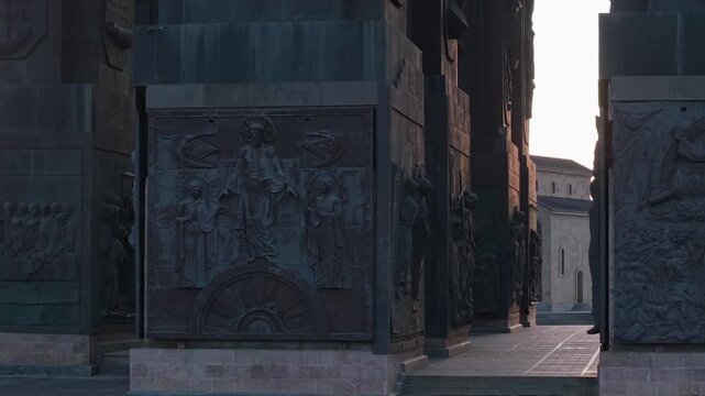 Drone reveal of the Annunciation Church framed by the monumental columns of the Chronicle of Georgia, captured in warm morning light with dramatic composition.