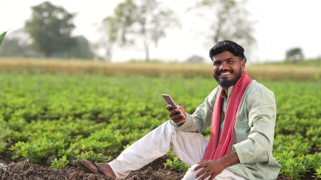 Indian farmer using smartphone at agriculture field 