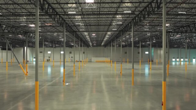 Wide reverse pullback aerial shot of the interior of an empty industrial warehouse in Lancaster, California. 4K