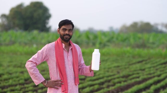 Indian farmer showing pesticide bottle at agriculture field 