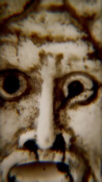 Ancient Roman Mouth of Truth mask, intentional shakiness and lighting variations, nightmare feelings. Vertical video. Haunting expression evokes mystery and terror.
