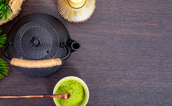 Matcha tea preparation with bamboo whisk and black iron teapot on wooden table. Traditional Japanese tea ceremony set for wellness and healthy lifestyle drink with copy space