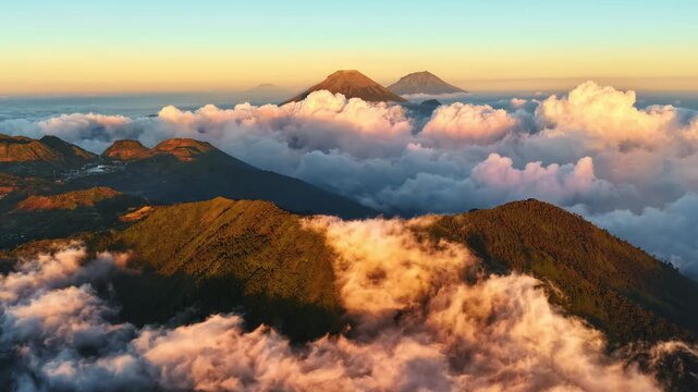 Aerial view of Sindoro Sumbing mountains surrounded by thick clouds at sunrise in Kecamatan Kedu, Jawa Tengah, Indonesia.
