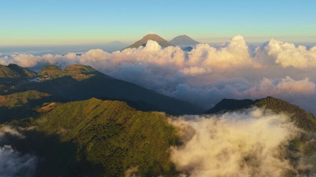 Aerial view of Sindoro Sumbing mountains rising above a sea of clouds in the morning light in Kecamatan Kedu, Jawa Tengah, Indonesia.