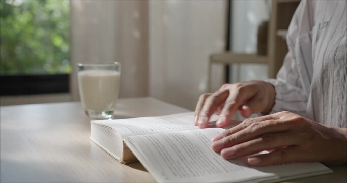 Close up. Hand Asian Woman reading Book on Table in Cozy Living Room, Slow Living Routine	