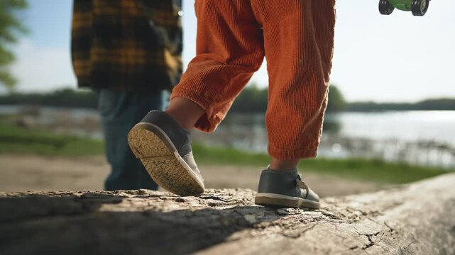 Toddler and father walk together family bonding. Family walk toddler steps with father guidance. Father and toddler enjoy family walk learning steps. Walk in park toddler with father family time.