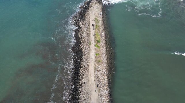 Aerial view of the stone breakwater at Logending Beach surrounded by ocean waves in Ayah, Central Java, Indonesia.