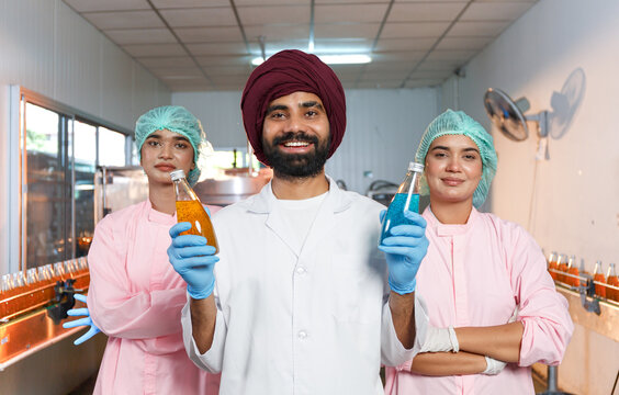 food engineering team Man and woman looking at camera inside glass bottle packaging machine room, factory